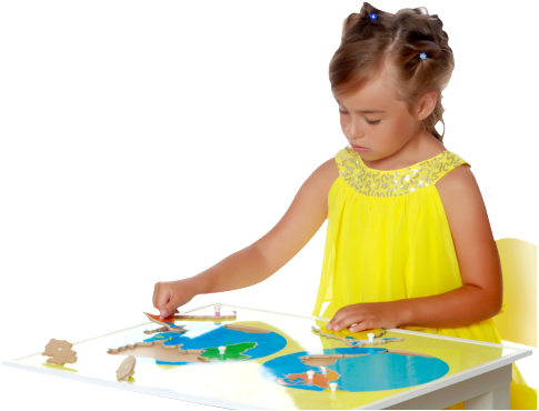 A little girl in kindergarten sits at a table and playing with puzzle