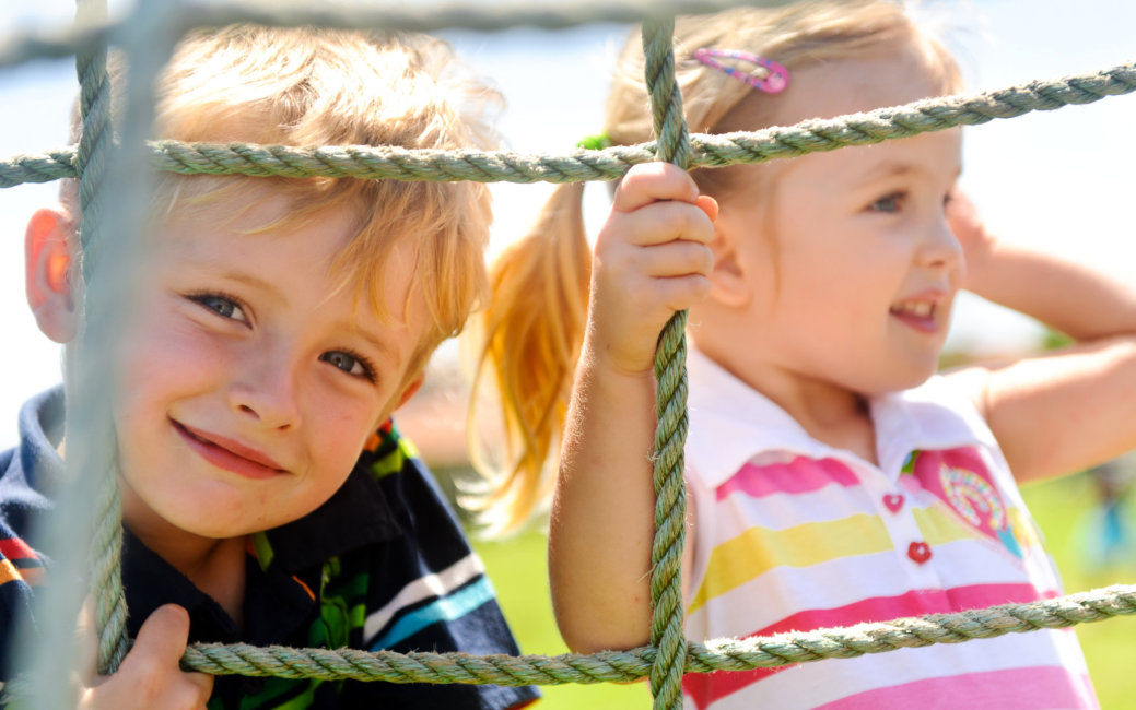 Two young children climbing the net in the playground
