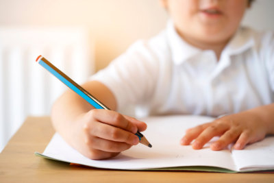 Blurry face of Kid holding pencil doing home work