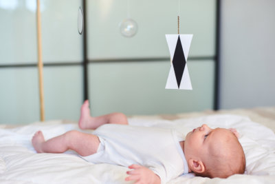 Adorable baby boy infant in white onesies, lying in bed