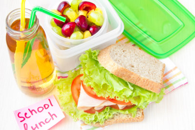 packed lunch for your child in school, box with a healthy sandwich and fruit salad and apple juice in the bottle for drinking 